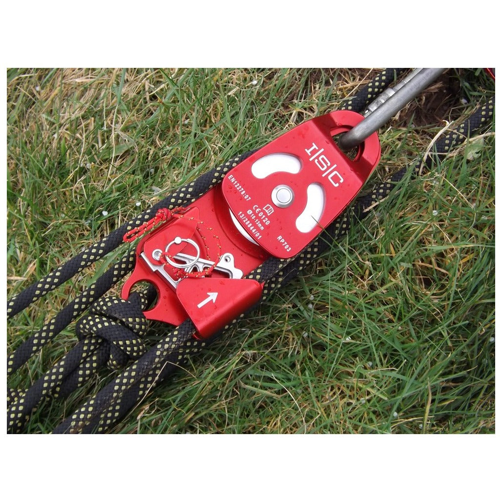 Red ISC RP703 double progress-capture pulley installed with black ropes and a gray connector on grass.